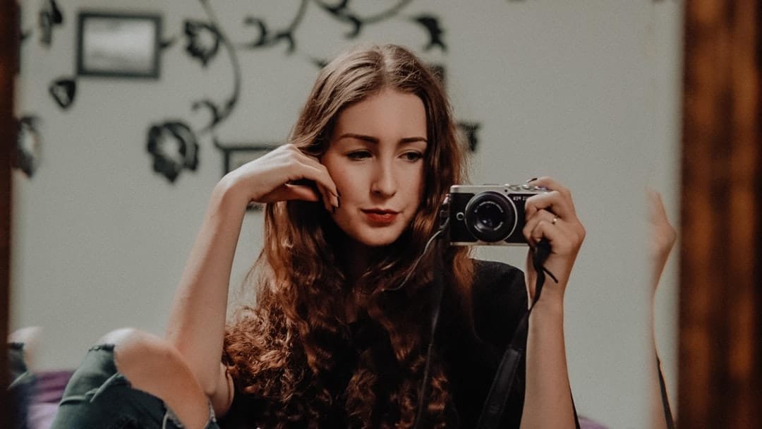 A woman standing in front of a mirror posing for the camera