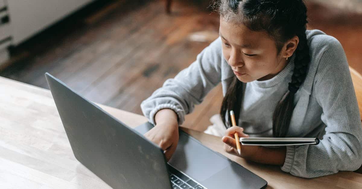 A young boy using a laptop computer sitting on top of a table